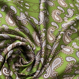 Gros plan sur la texture du satin vert à motif paisley et les détails en soie
