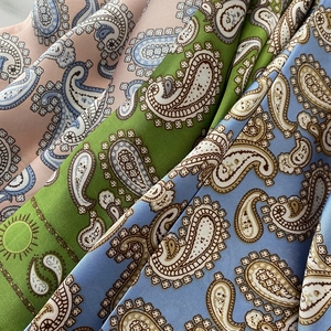 Gros plan de foulards en soie à motif paisley en satin rose, vert et bleu clair