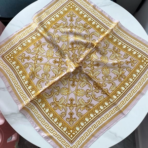 Pink satin square scarf with golden baroque floral patterns on marble background