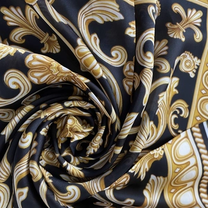 Macro detail of satin silk scarf featuring baroque golden patterns on black fabric