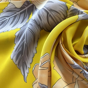 Detail of bright yellow floral satin fabric showing soft texture and glossy finish