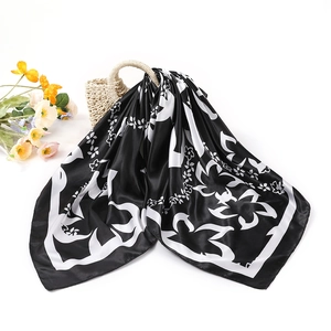 Élégant carré de soie satiné noir et blanc à motif floral sur un sac en paille