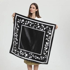 Elegant black silk scarf with white leaf patterns shown on model in a front studio view