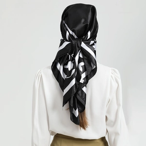 Detail of a black silk scarf with leaf print draped over a stylish white puff sleeve top