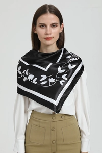 Close-up of elegant black silk scarf with white leaf patterns and geometric borders