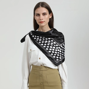Elegant black silk scarf with white polka dots worn by a model on a light background