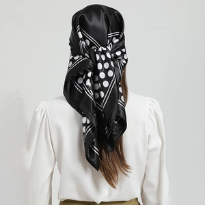 Detail of silk-like black headscarf with large white polka dots worn in a head-tied style