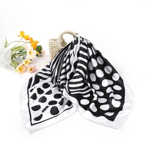 Foulard élégant en soie noir et blanc à motifs géométriques posé sur un sac tressé
