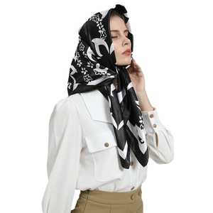 Élégant foulard en satin noir et blanc à fleurs porté comme bandeau par un mannequin