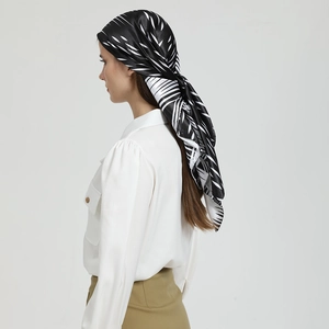 Détail d'un foulard en soie avec motif de feuilles blanches sur satin noir