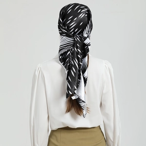 Détail d'un foulard en soie à motif de feuilles porté en châle sur un chemisier blanc