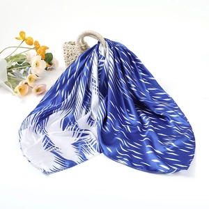 Élégant foulard en soie bleu et blanc à motifs géométriques sur un sac en paille