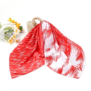 Carré de soie rouge et blanc avec motif géométrique de feuilles drapé sur un sac