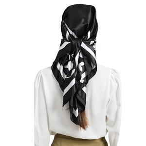 Elegant black silk square scarf featuring white leaf prints worn as a stylish headscarf