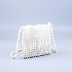Détail d'un sac en perles blanches tressé à la main avec pompon et bandoulière longue