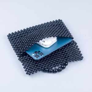 Detail of black acrylic beaded bag showing storage capacity for phone and earphones
