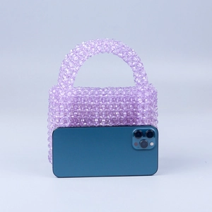 Detail of purple beaded handmade bag showing scale next to a smartphone