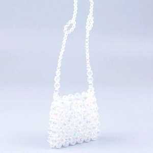 Gros plan des perles acryliques irisées et texture tissée main du mini sac à main