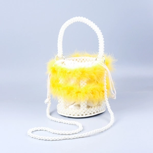 Detailed close-up of woven faux pearls and yellow feather trim on a handmade bucket bag