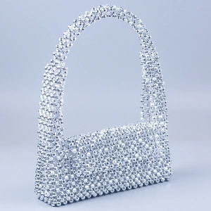 Detail of hand-woven silver faceted beads and top handle on a stylish flap handbag