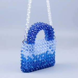 Close-up of blue gradient acrylic beads and chain on a handmade woven handbag