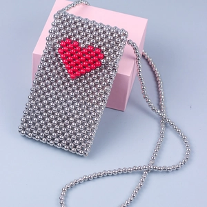 Detail of silver beaded phone bag with red heart pattern and crossbody strap