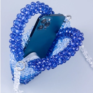 Detail of gradient blue beaded handbag with phone inside showing internal capacity