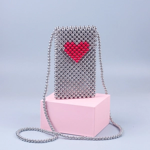Detail of handmade silver beaded crossbody phone bag with red heart pattern decoration