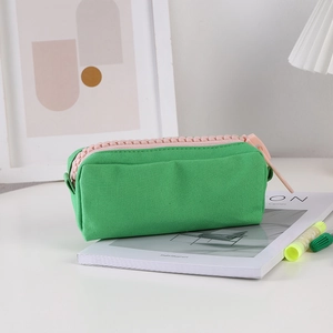 Detail of green canvas pencil case featuring a large pink plastic chunky zipper