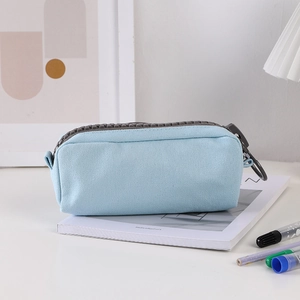 Detailed close-up of light blue canvas pencil case with a chunky grey zipper on a desk