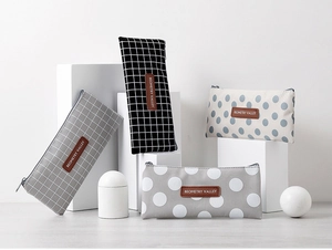 Detail of four canvas pencil cases with grid and dot patterns and leather labels
