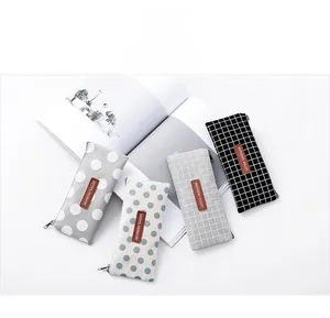 Macro detail of canvas pencil cases featuring polka dots, grids, and leather patch logo