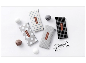 Flat lay of canvas pencil cases in grid and polka dot patterns with leather labels