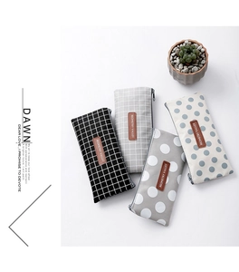 Detail view of four checkered and polka dot canvas pencil cases with leather logo patches