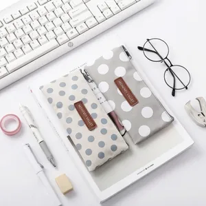 Minimalist canvas pencil cases with polka dot pattern and leather logo on a desk