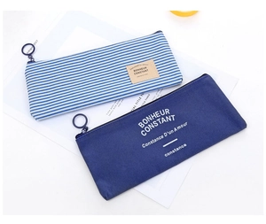 Detail of striped and navy blue oxford pencil cases with large circular metal zippers