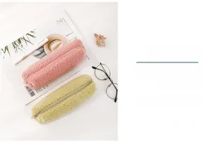 Pink and yellow fleece pencil cases with zipper closure on a cozy desktop setting