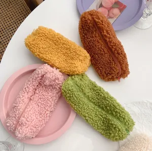 Fuzzy lamb wool pencil case in yellow brown pink and green colors on pink tray