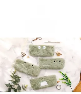 Detail of four soft plush dinosaur pencil cases with cute expressions on marble background