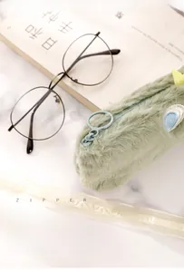 Detail of mint green plush pencil case featuring a metal ring zipper and eye embroidery