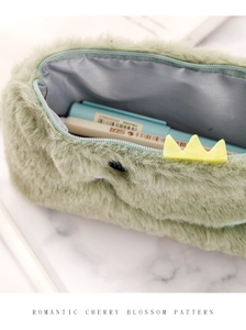Detail of mint green plush pencil case with yellow crown patch and zipper closure