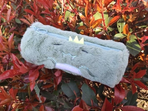 Detailed view of the plush dinosaur pencil case featuring soft fur and 3D back spines
