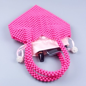 Vue macro d'un sac à main fait main en perles rose vif avec doublure en satin et perles lisses