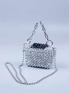 Detail of silver beaded handbag with metallic chain handle and contrasting black accents