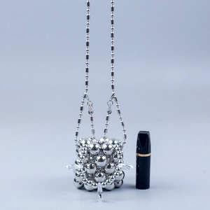 Detail van handgemaakte zilveren mini-tas met metalen kralen en een fijne ketting