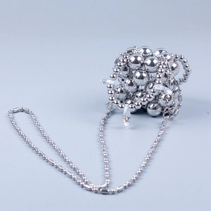 Detail van zilveren kralen crossbodytas met metalen ketting en kristallen druppels