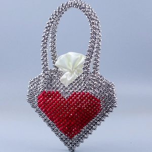 Close-up of handmade silver beaded handbag with a red heart pattern and satin drawstring
