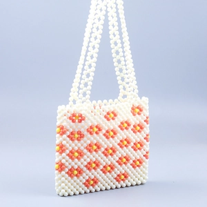 Detail of hand-woven beaded bag with floral patterns on a minimal blue background