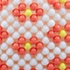 Macro view of handmade red flower beadwork detail on white woven shoulder bag