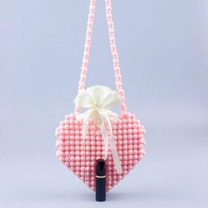 Detail view of pink heart-shaped beaded handbag with satin drawstring liner and lipstick